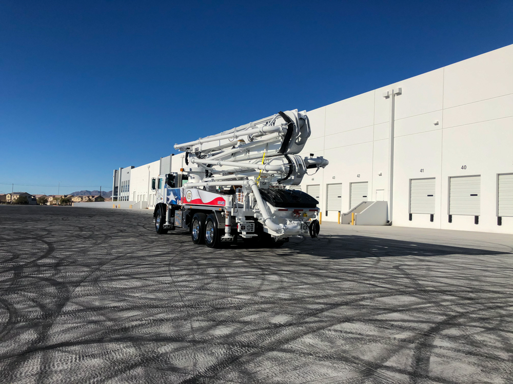 DY Concrete Pumps manufactured boom pump with MBR logo and flag design on display outside of the WOC event