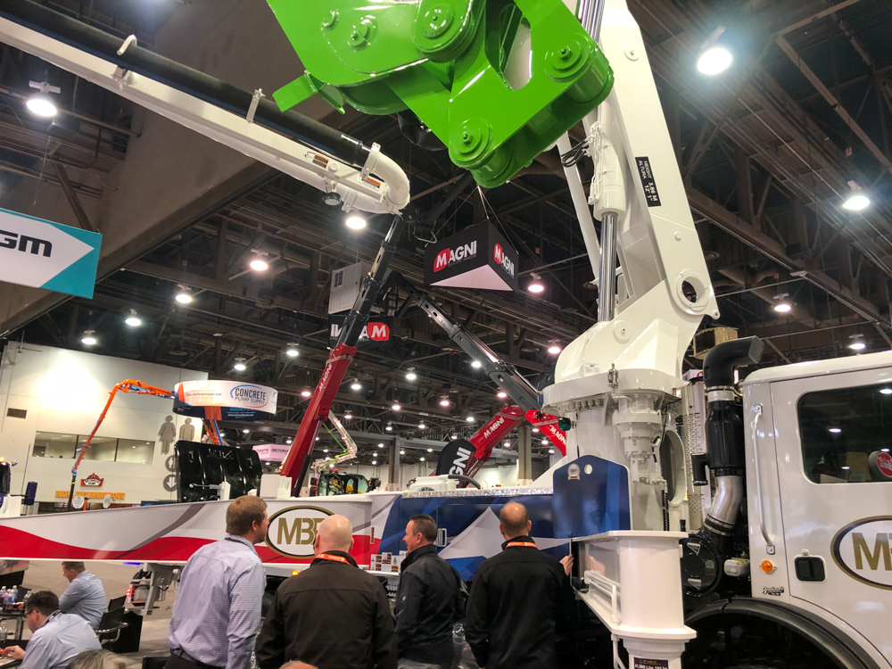 four men looking at a DY concrete pump at the World of Concrete event