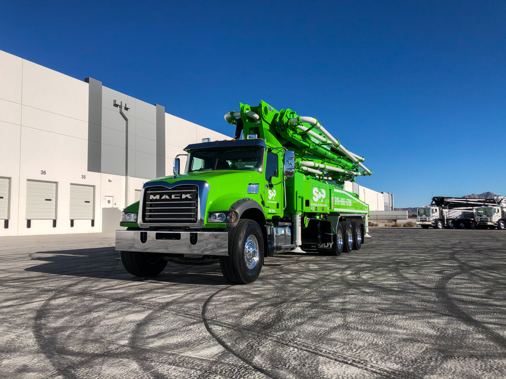 front of a lime green DY concrete pump displayed outside of the WOC event